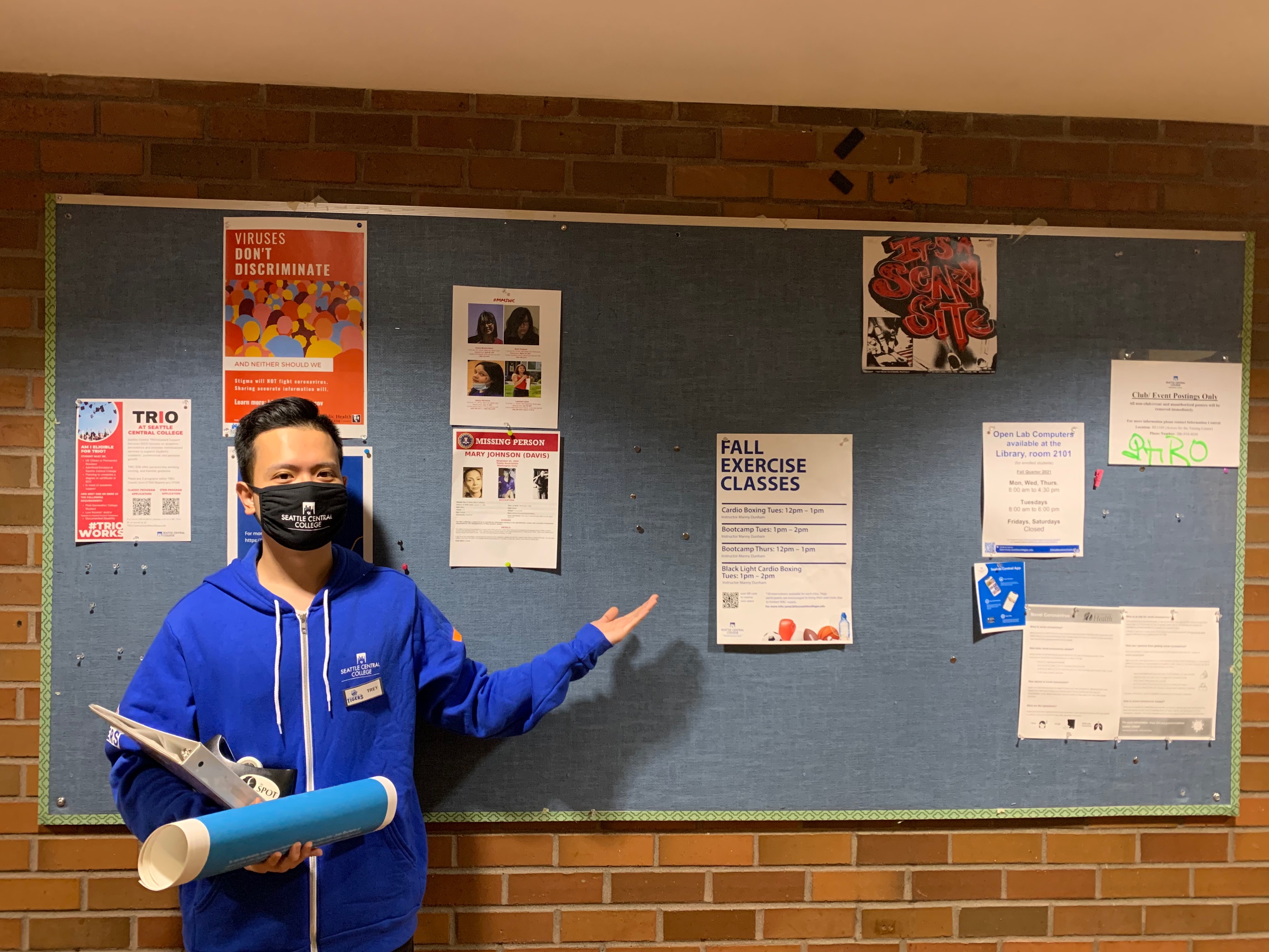 student standing in front of poster board pointing at poster